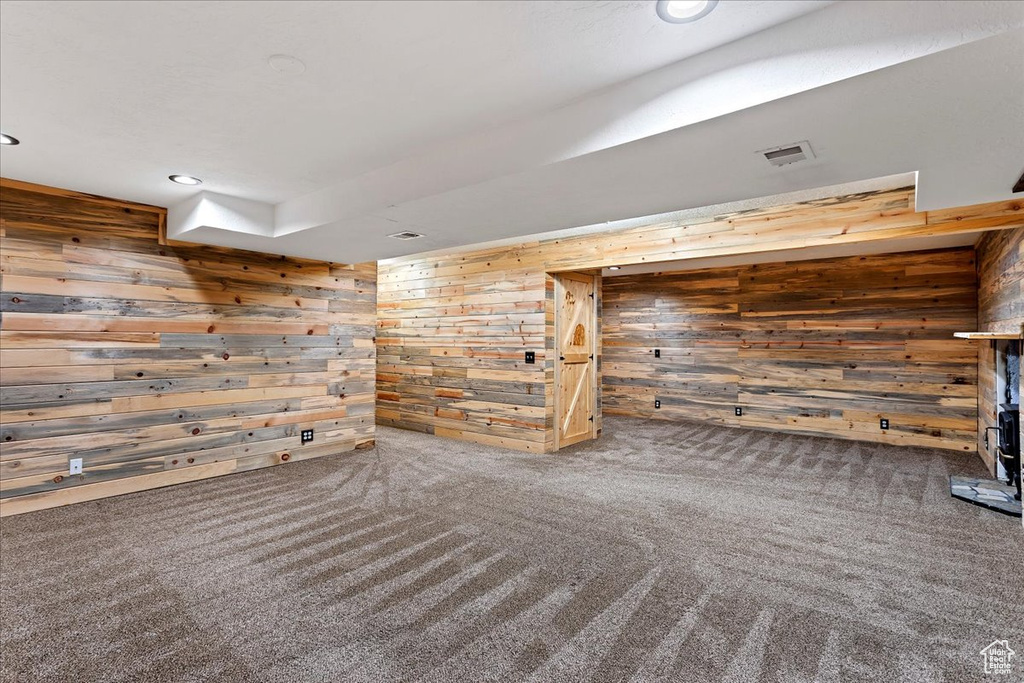 Carpeted empty room featuring wooden walls