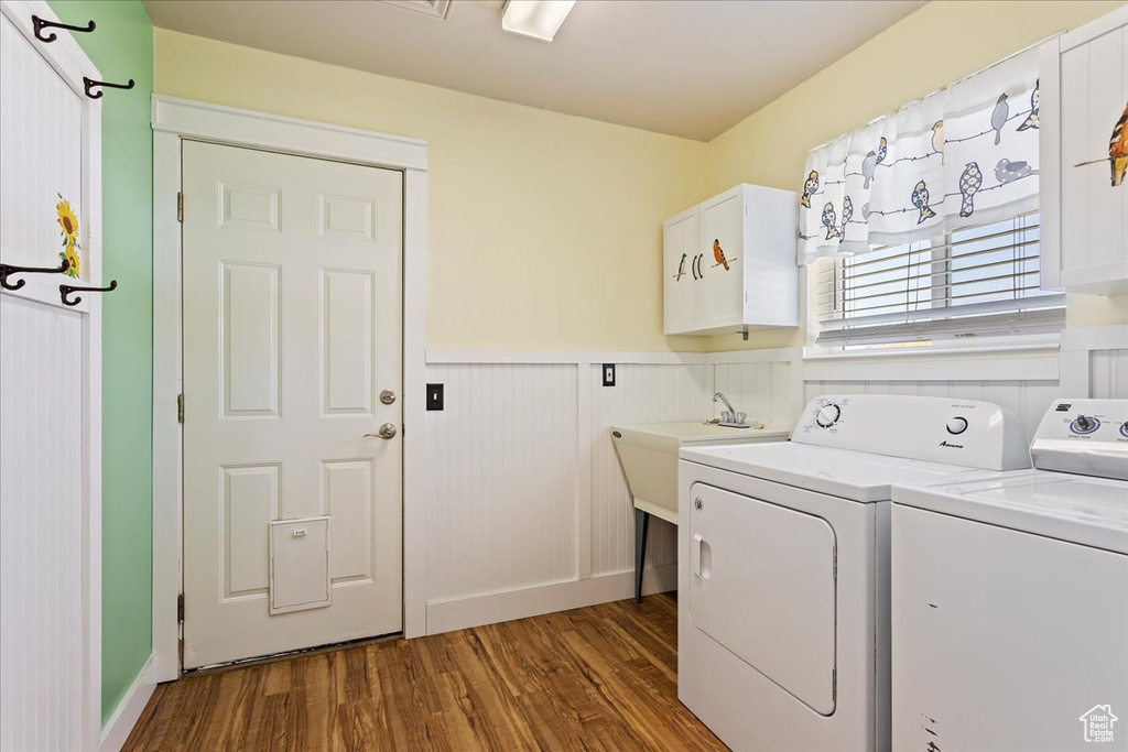 Laundry room with cabinets, washing machine and dryer, dark hardwood / wood-style floors, and sink