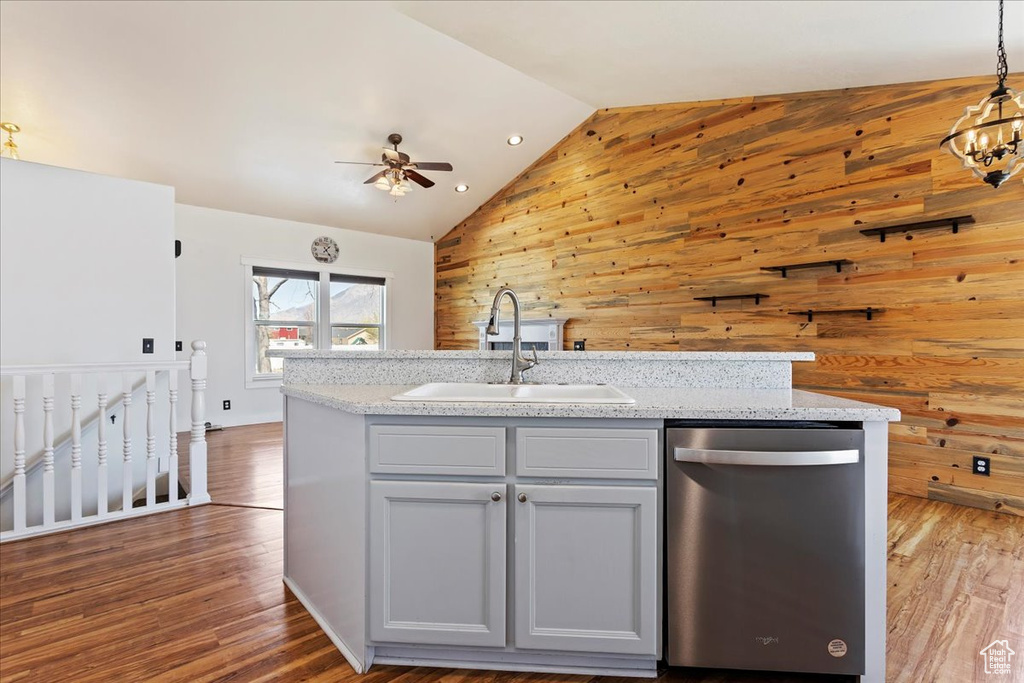 Kitchen with wood walls, vaulted ceiling, dishwasher, and decorative light fixtures