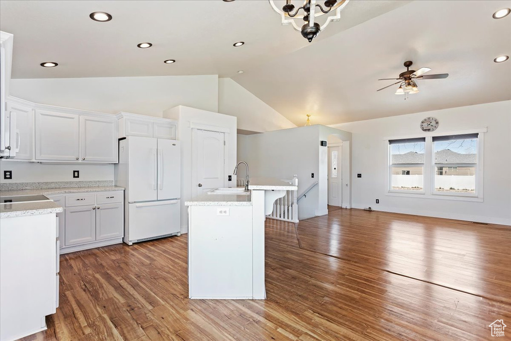 Kitchen with a kitchen island with sink, white fridge, white cabinetry, and hardwood / wood-style flooring