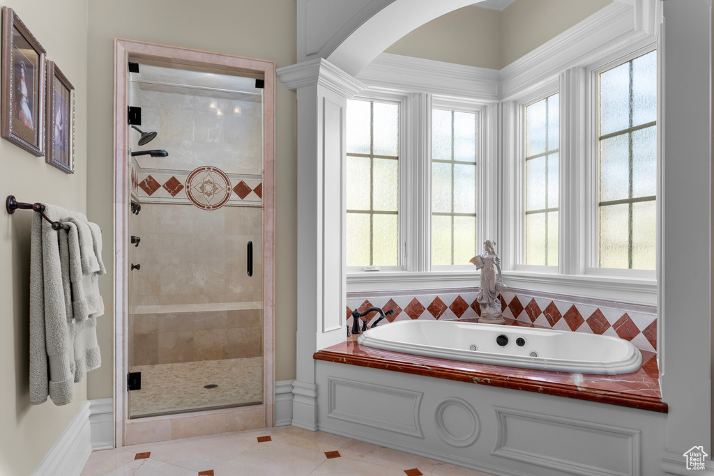 Bathroom featuring shower with separate bathtub and tile flooring