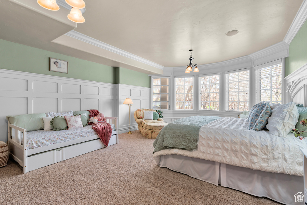 Bedroom featuring light colored carpet, a tray ceiling, crown molding, and an inviting chandelier