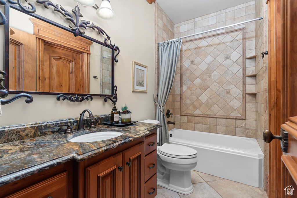 Full bathroom with shower / bath combo, toilet, tile floors, and large vanity