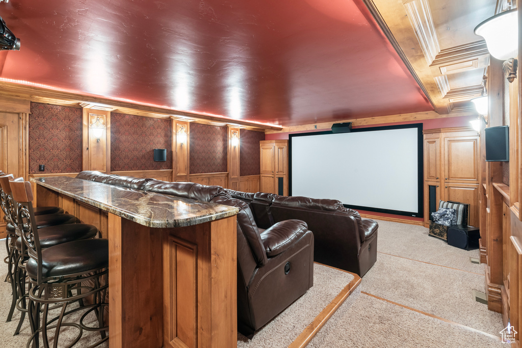 Home theater with ornamental molding, light colored carpet, wooden walls, and bar area