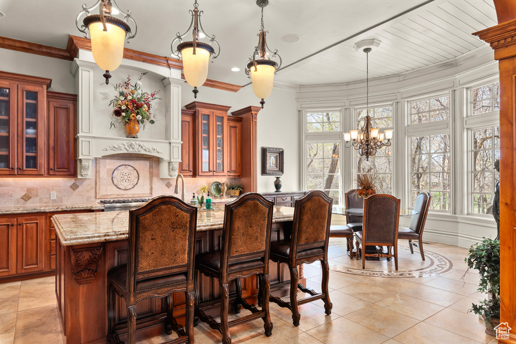 Bar featuring light stone counters, tasteful backsplash, pendant lighting, and a wealth of natural light