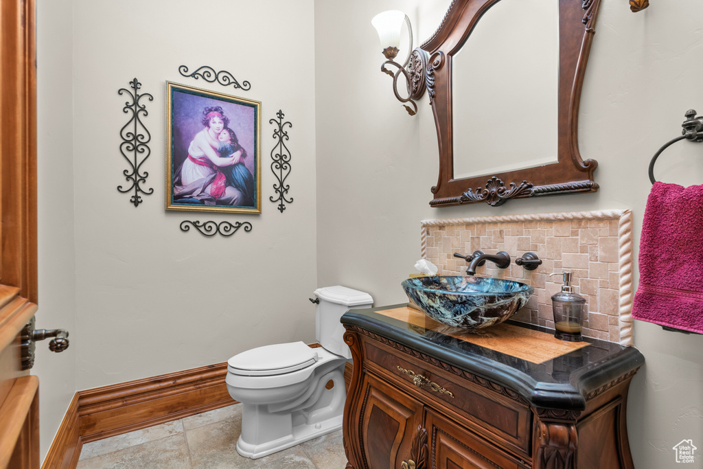 Bathroom featuring tasteful backsplash, vanity, tile floors, and toilet
