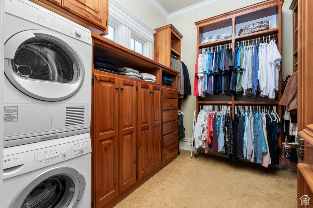 Clothes washing area featuring cabinets, stacked washer / dryer, and light carpet