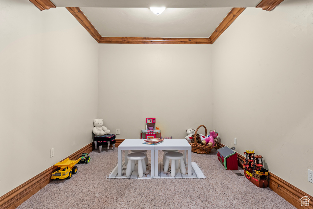 Playroom with ornamental molding and light colored carpet