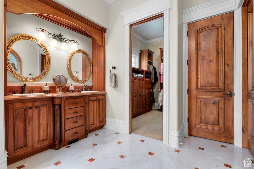 Bathroom with dual sinks, ornamental molding, tile floors, and large vanity