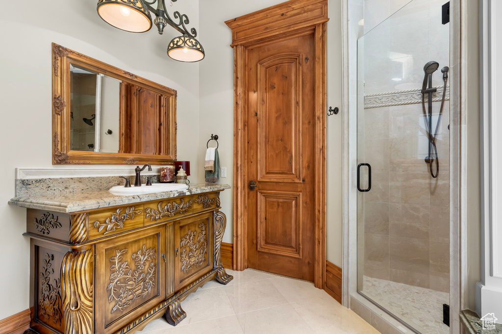 Bathroom with vanity with extensive cabinet space, a shower with door, and tile floors