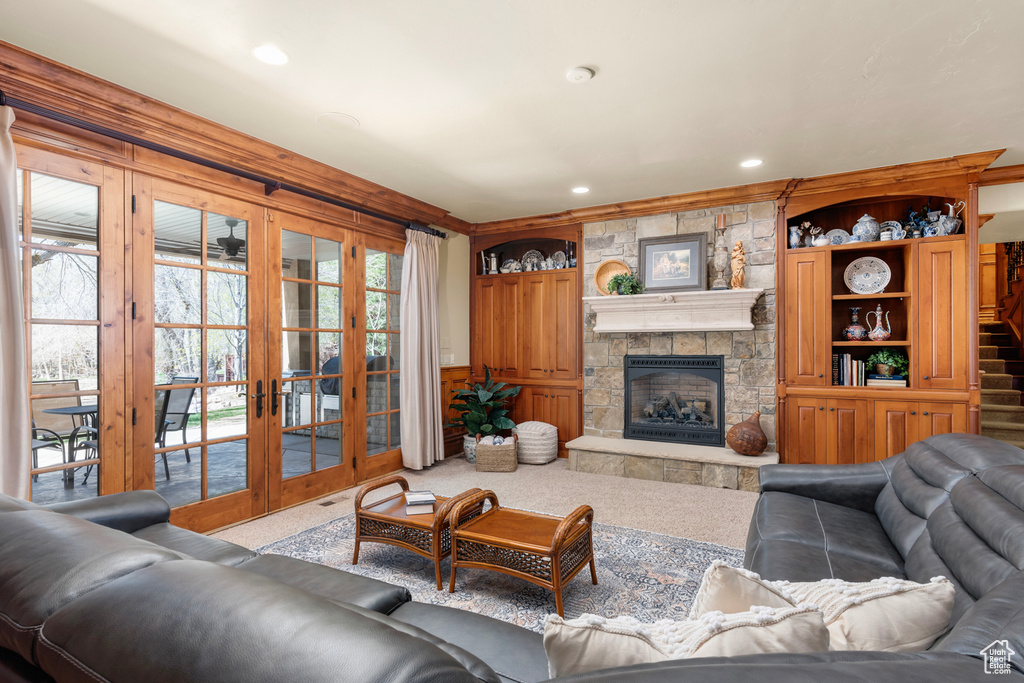 Living room with light carpet, french doors, and a stone fireplace