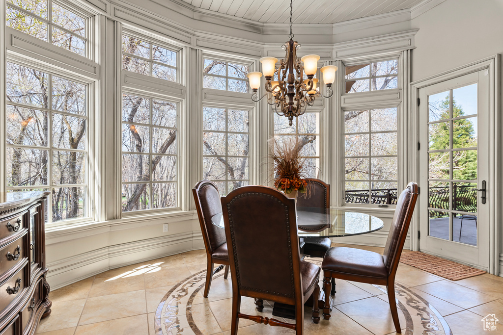 Dining room featuring light tile flooring, crown molding, and an inviting chandelier