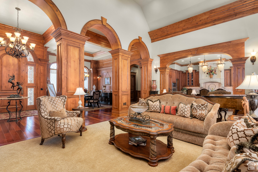 Living room featuring ornate columns, dark hardwood / wood-style flooring, a notable chandelier, and a high ceiling