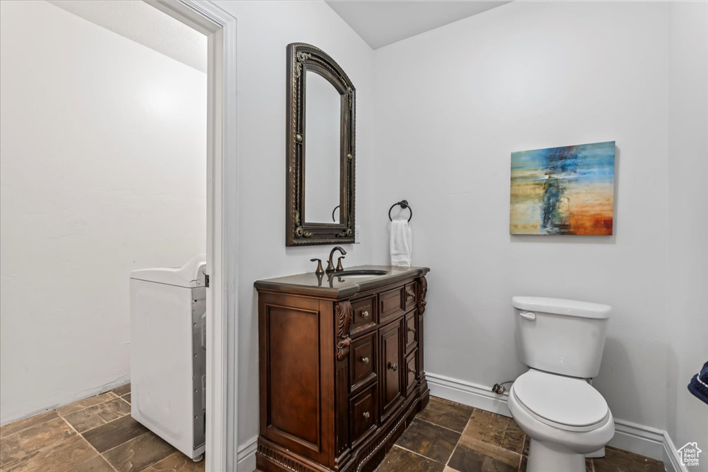 Bathroom featuring tile floors, vanity, toilet, and washer / dryer