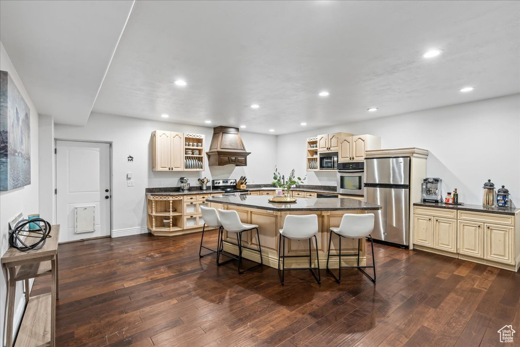 Kitchen featuring a center island, stainless steel appliances, a kitchen breakfast bar, and dark wood-type flooring
