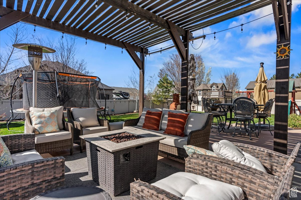 View of terrace with a pergola, an outdoor living space with a fire pit, and a trampoline