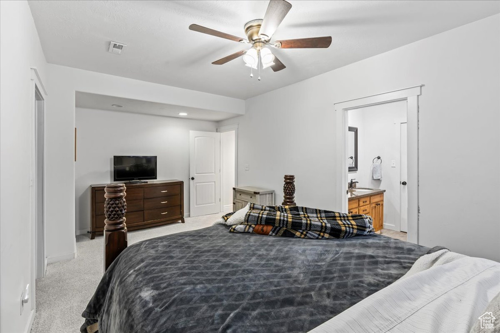 Carpeted bedroom featuring ensuite bath, ceiling fan, and sink