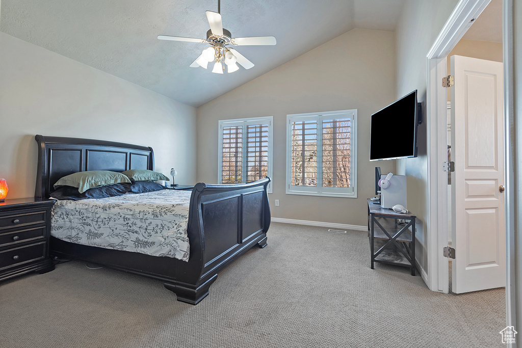 Bedroom featuring ceiling fan, light carpet, and high vaulted ceiling