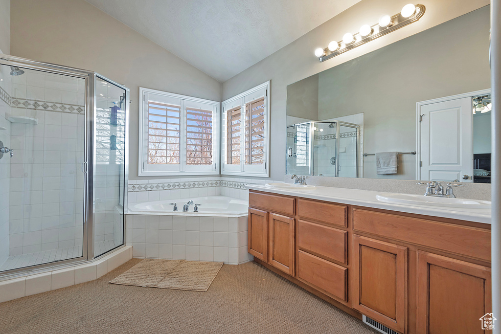 Bathroom featuring separate shower and tub, dual bowl vanity, and lofted ceiling