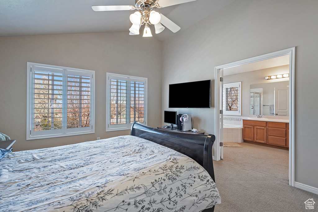 Bedroom featuring ensuite bath, light carpet, ceiling fan, and lofted ceiling