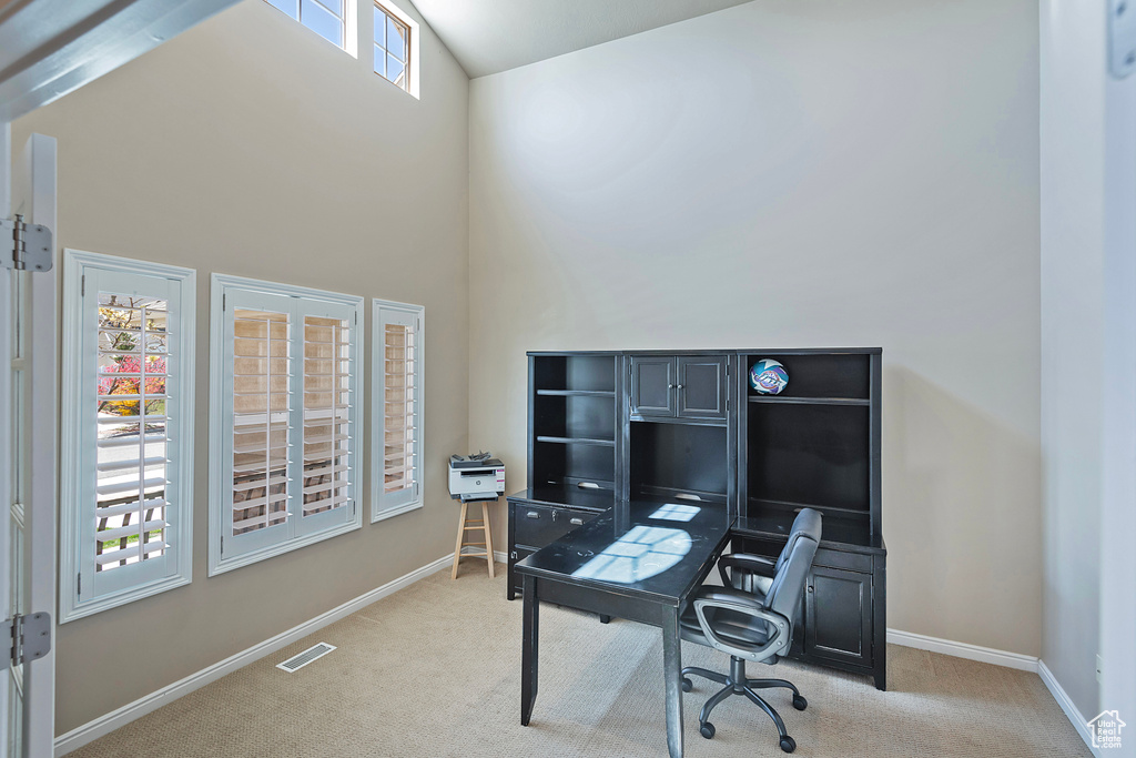 Home office featuring light colored carpet and high vaulted ceiling