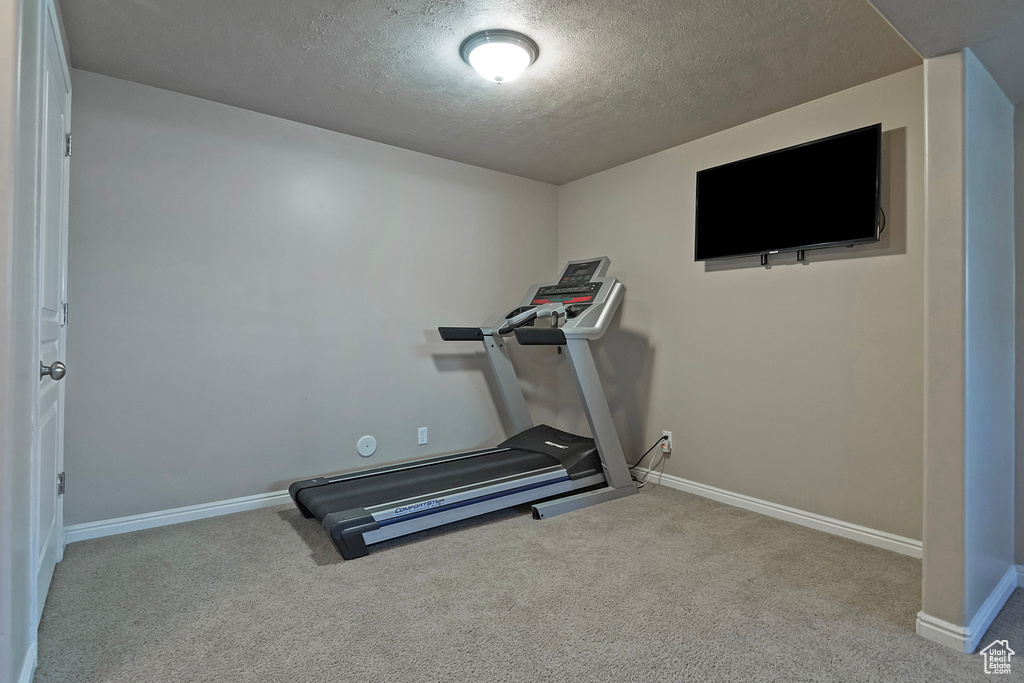 Exercise room featuring light colored carpet and a textured ceiling