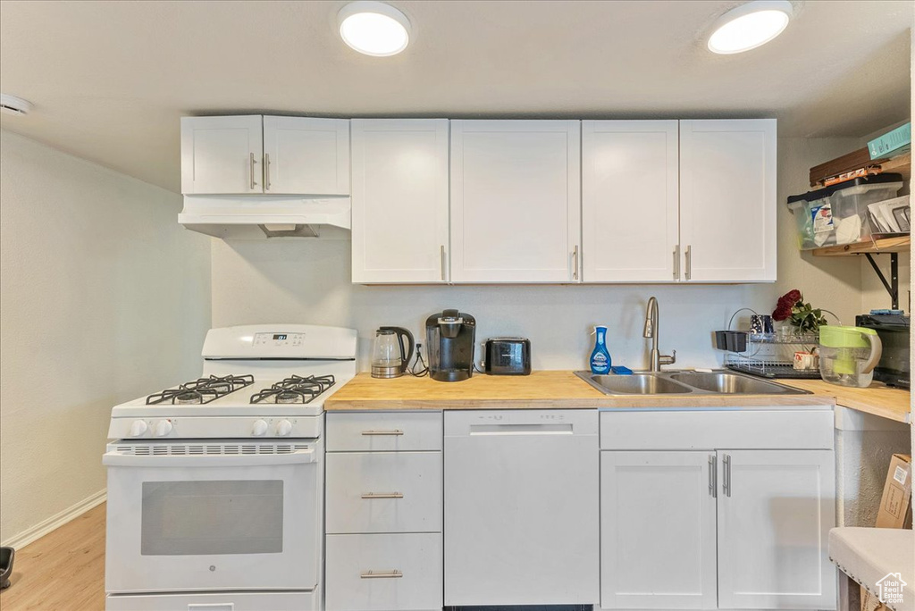 Kitchen with white cabinets, white appliances, and custom exhaust hood