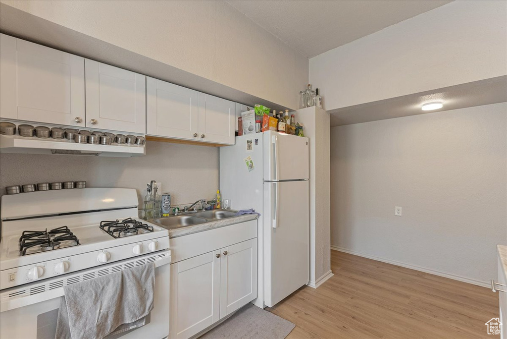 Kitchen with extractor fan, white appliances, white cabinets, light wood-type flooring, and sink