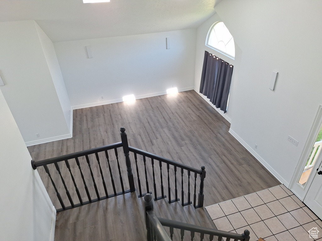 Staircase with a healthy amount of sunlight, dark tile floors, and vaulted ceiling