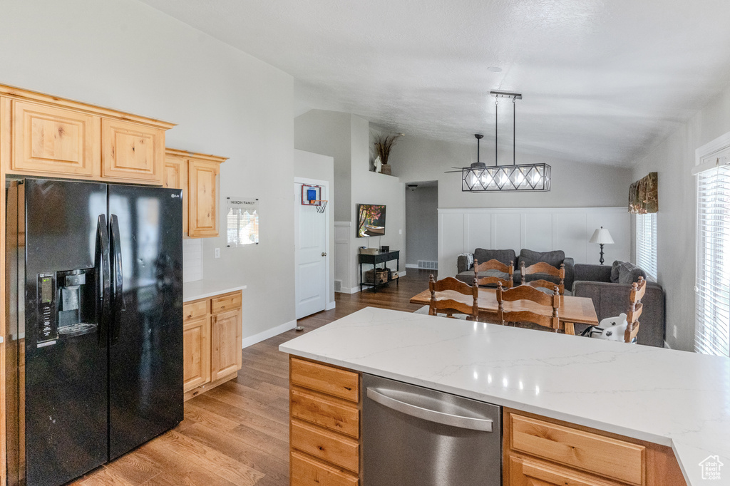 Kitchen featuring black fridge, stainless steel dishwasher, lofted ceiling, light hardwood / wood-style flooring, and pendant lighting