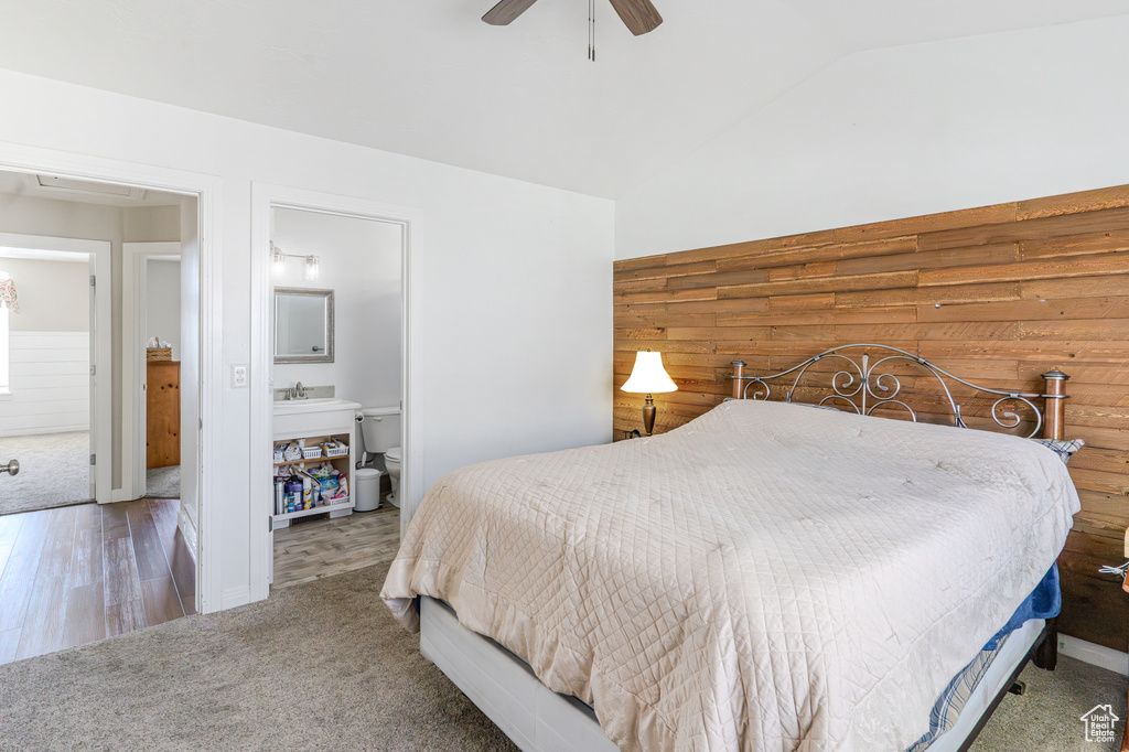 Bedroom featuring ceiling fan, ensuite bathroom, sink, lofted ceiling, and dark hardwood / wood-style floors