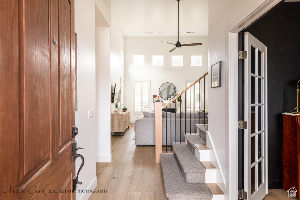 Entryway featuring light hardwood / wood-style flooring, ceiling fan, and a towering ceiling