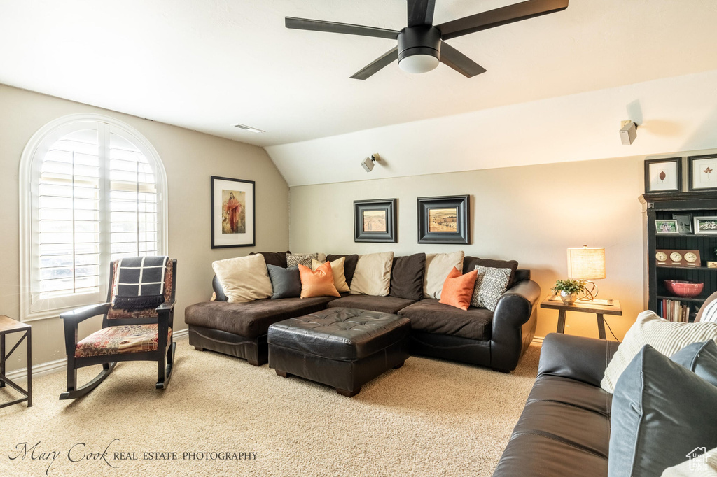 Carpeted living room with lofted ceiling and ceiling fan