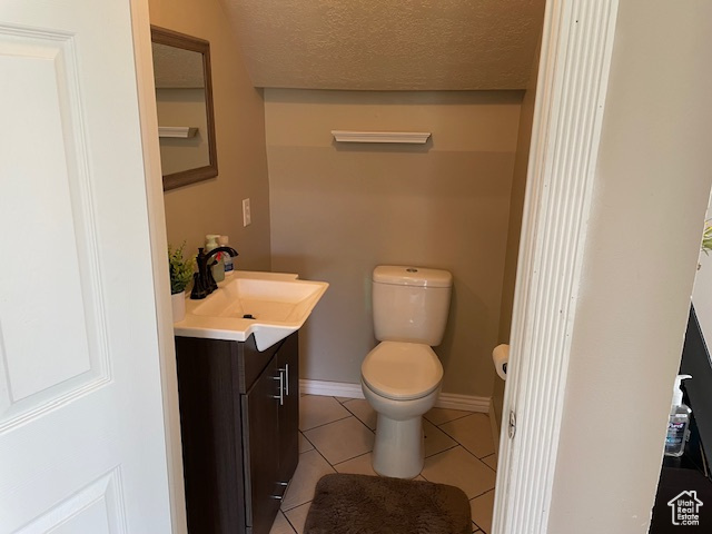 Bathroom with a textured ceiling, vanity, tile floors, and toilet