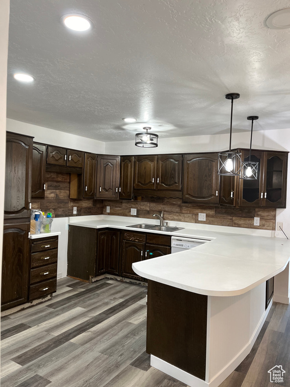 Kitchen with pendant lighting, dark wood-type flooring, dark brown cabinets, and sink