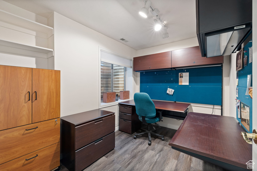 Office space with built in desk, light hardwood / wood-style floors, and rail lighting
