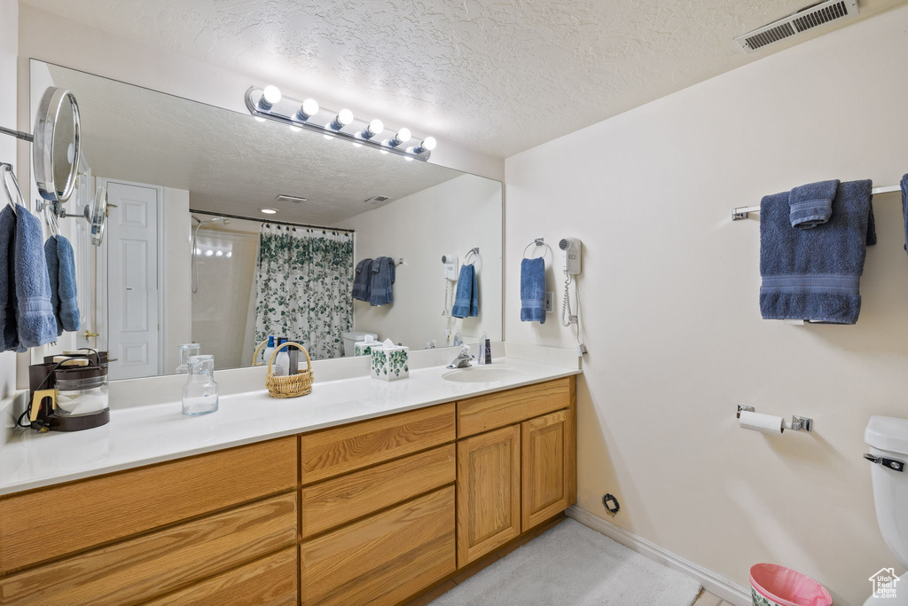 Bathroom with a textured ceiling, oversized vanity, and toilet
