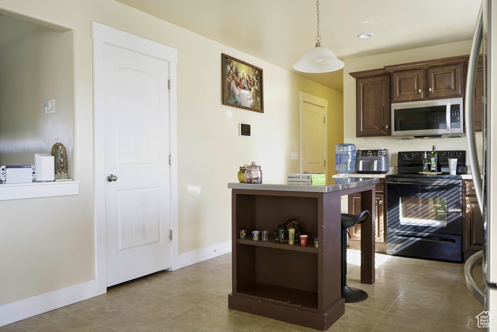 Kitchen featuring dark brown cabinetry, pendant lighting, stainless steel appliances, and light tile flooring