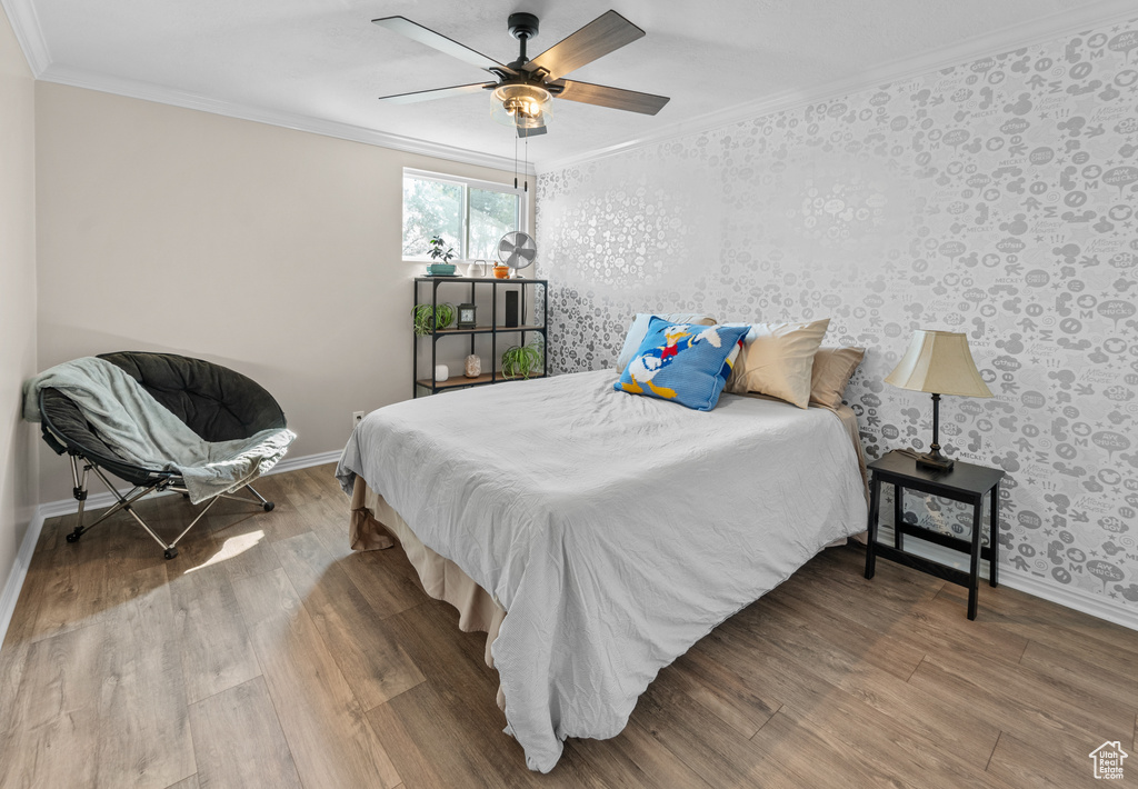 Bedroom with ceiling fan, ornamental molding, and hardwood / wood-style floors