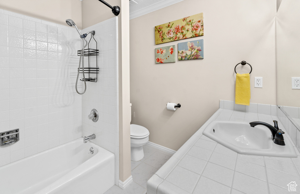 Full bathroom with tile floors, sink, toilet, tiled shower / bath, and crown molding