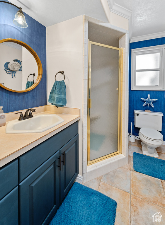 Bathroom with toilet, a shower with shower door, vanity, ornamental molding, and tile floors