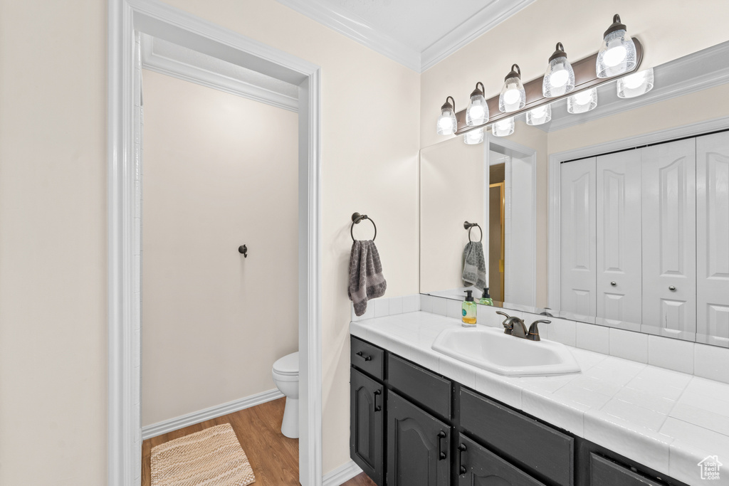 Bathroom with crown molding, toilet, hardwood / wood-style flooring, and vanity