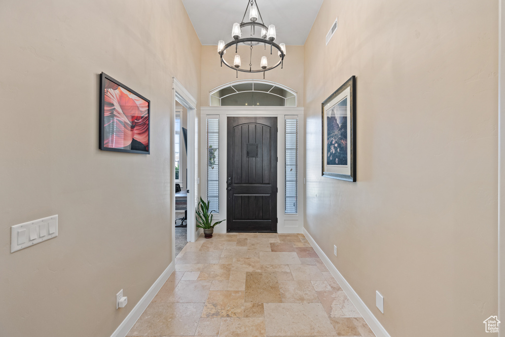 Tiled entryway featuring an inviting chandelier