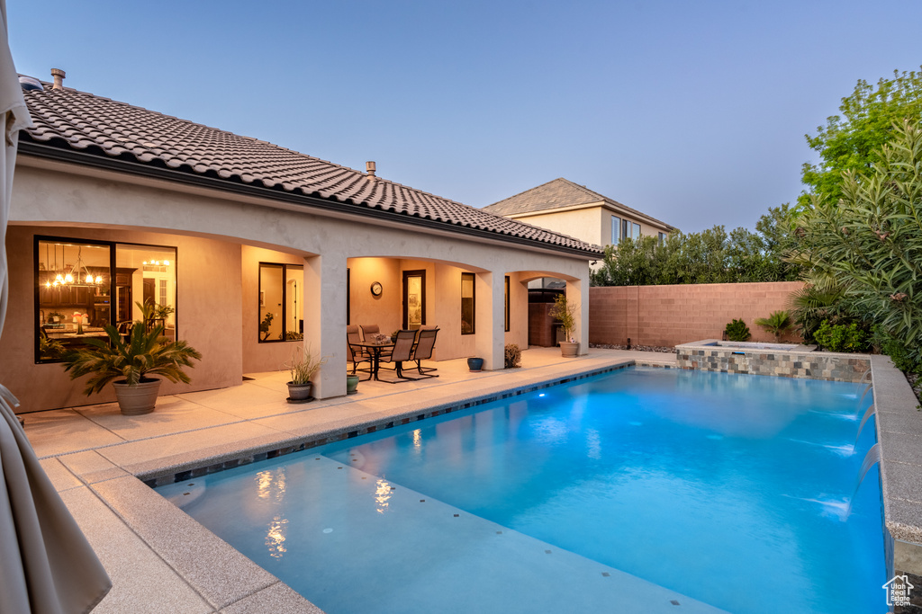 Pool at dusk with a patio area and pool water feature