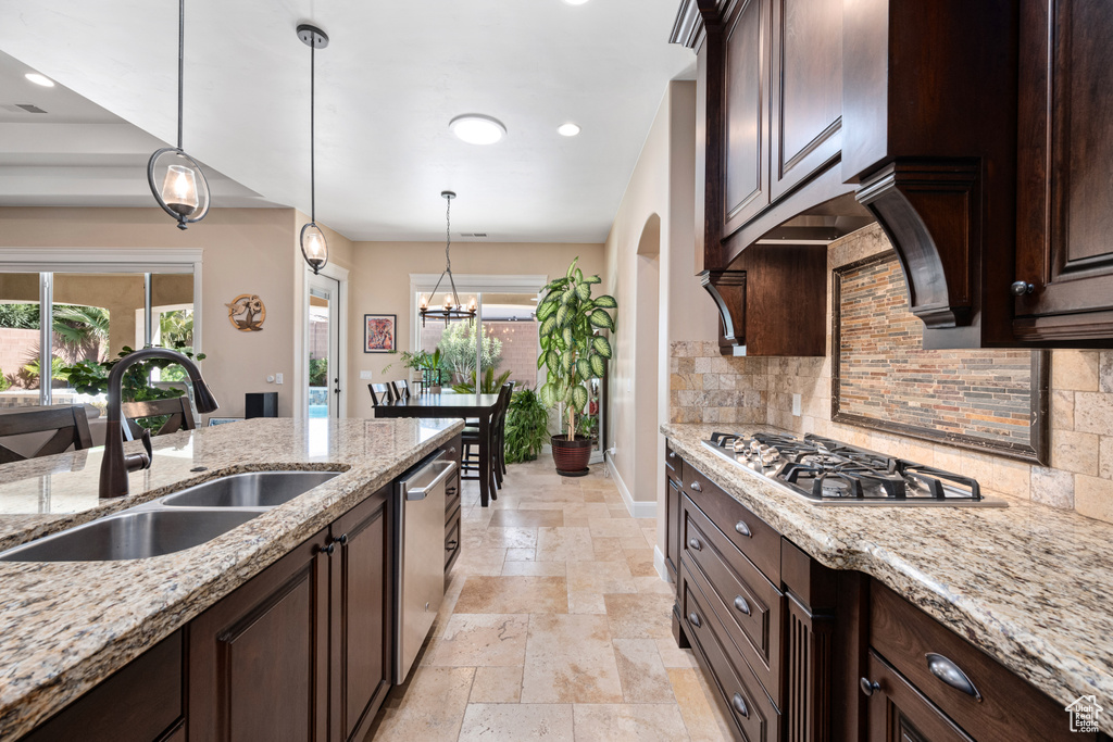 Kitchen with pendant lighting, light stone countertops, light tile floors, sink, and tasteful backsplash