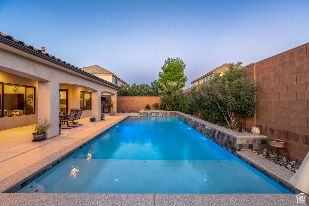 Pool at dusk with a patio area and pool water feature