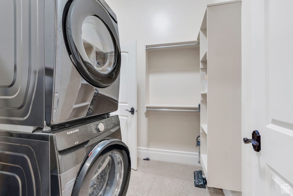 Laundry area featuring light carpet and stacked washer / dryer