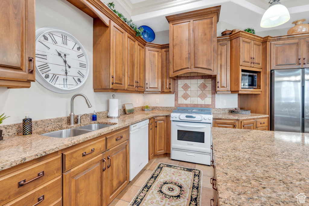 Kitchen featuring appliances with stainless steel finishes, backsplash, light stone counters, sink, and light tile floors
