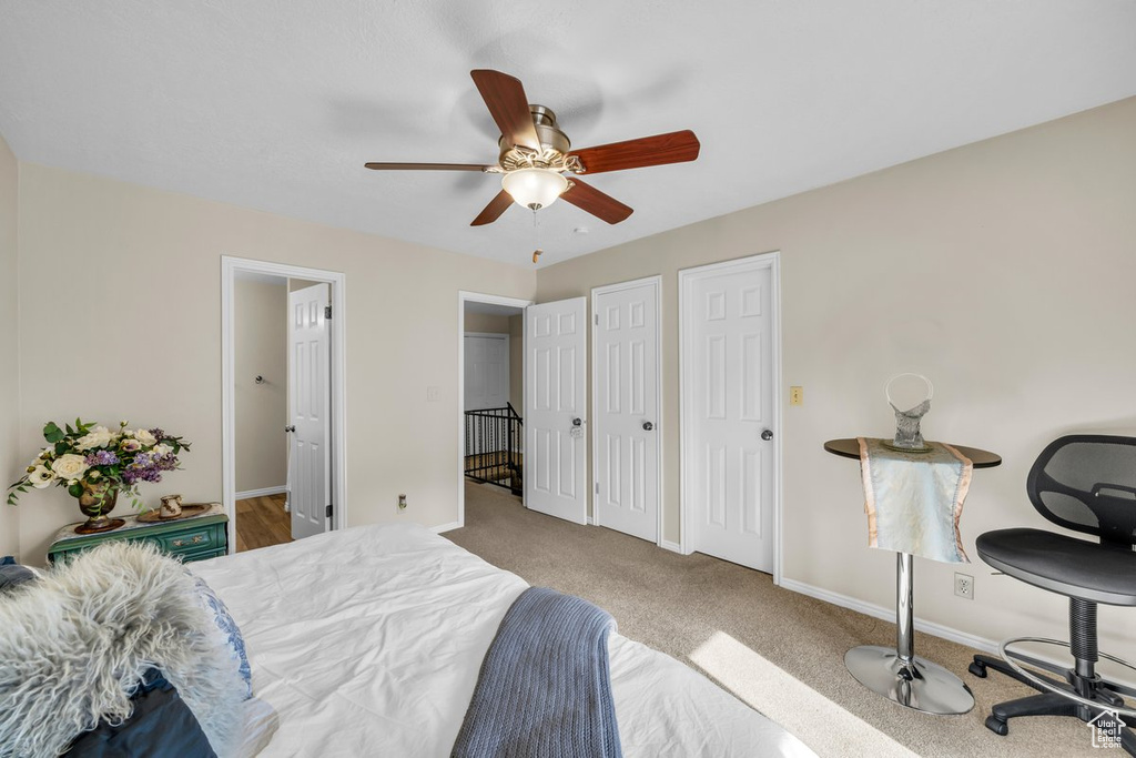 Bedroom with multiple closets, ceiling fan, and light carpet