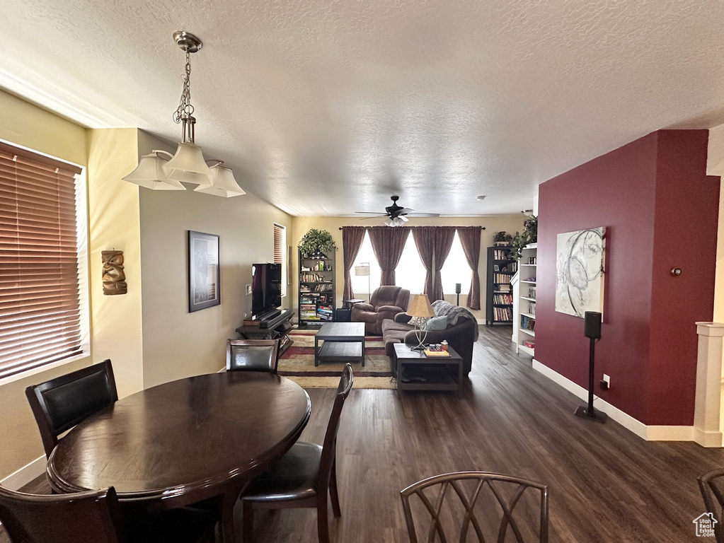 Dining space featuring dark wood-type flooring, ceiling fan, and a textured ceiling